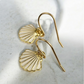 Dainty gold seashell dangle drop earrings. Perfect for beach inspired or ocean-themed jewelry lovers.